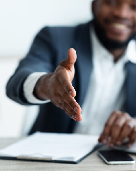 Partnership concept. Smiling young African American businessman extending hand to shake.