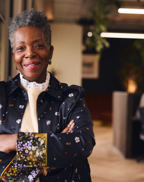 Portrait of confident senior black woman smiling and looking at camera with arms folded